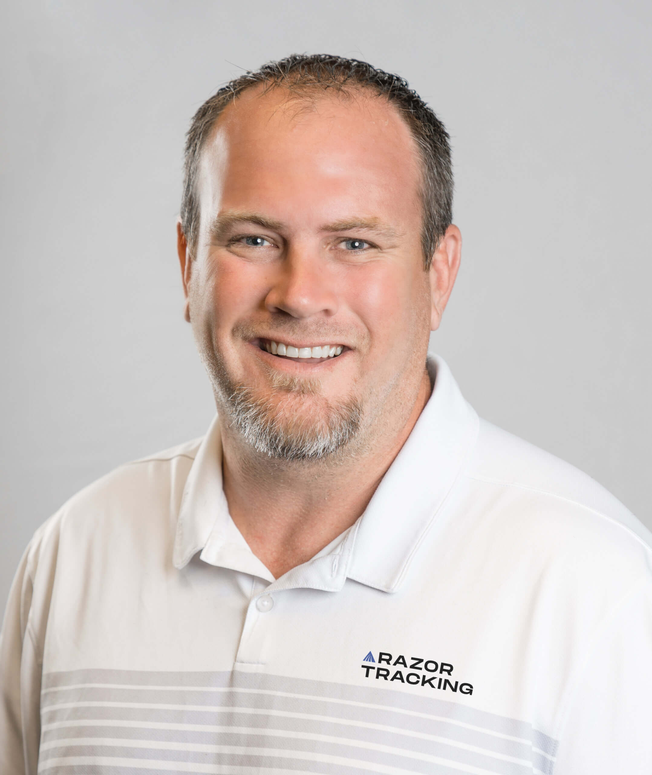 Eric posing for a studio headshot. He is wearing a white Razor Tracking polo.